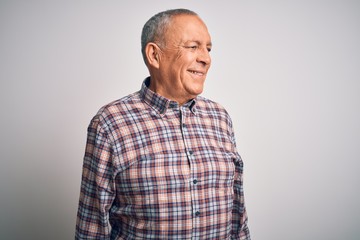 Senior handsome man  wearing casual shirt standing over isolated white background looking away to side with smile on face, natural expression. Laughing confident.