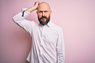 Obraz premium Handsome bald man with beard wearing elegant shirt over isolated pink background confuse and wonder about question. Uncertain with doubt, thinking with hand on head. Pensive concept.