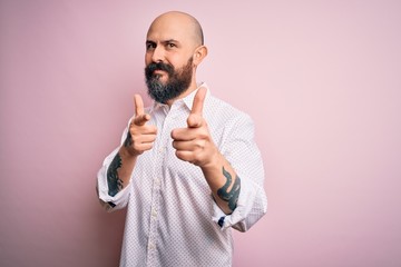 Handsome bald man with beard wearing elegant shirt over isolated pink background pointing fingers to camera with happy and funny face. Good energy and vibes.