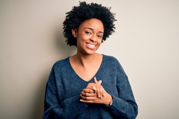 Young beautiful African American afro woman with curly hair wearing casual sweater with hands together and crossed fingers smiling relaxed and cheerful. Success and optimistic