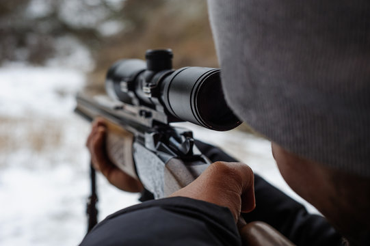 Man holding a sniper and shooting on an open season, looking through scope