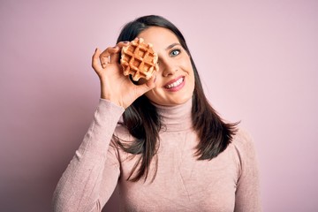 Young brunette woman with blue eyes eating sweet waffle for breakfast over white background with a...