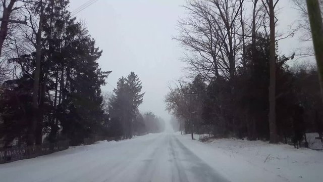 *Reverse Motion* Driving Winter Snow Storm Backward in Residential Suburb in Day.  Driver Point of View POV Snowing Blizzard Snowfall on Suburban Road.