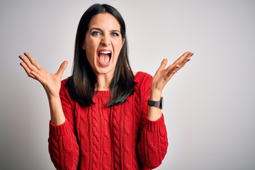 Young brunette woman with blue eyes wearing casual sweater over isolated white background celebrating crazy and amazed for success with arms raised and open eyes screaming excited. Winner concept