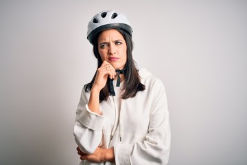 Young cyclist woman with blue eyes wearing bike helmet over isolated white background with hand on chin thinking about question, pensive expression. Smiling with thoughtful face. Doubt concept.