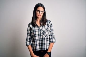 Young brunette woman with blue eyes wearing casual shirt and glasses over white background skeptic and nervous, frowning upset because of problem. Negative person.