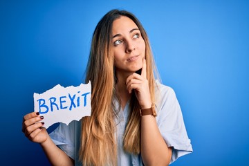 Young beautiful blonde woman with blue eyes holding banner with brexit message serious face...