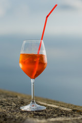 Aperol spritz with straw and ice cubes on the balcony 