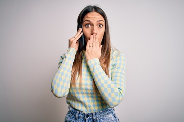 Young blonde woman having a conversation talking on smartphone over isolated background cover mouth with hand shocked with shame for mistake, expression of fear, scared in silence, secret concept