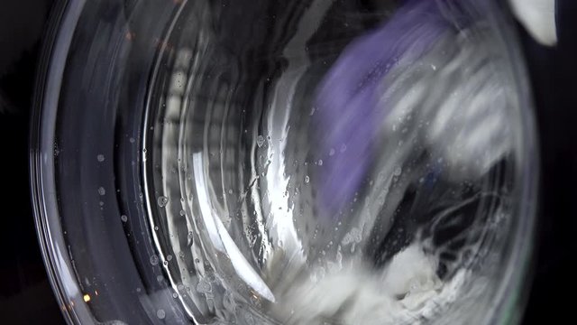 The washing machine is working. A washing machine spins a drum filled with clothes. Drum close up.
