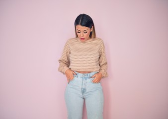Young beautiful woman wearing fashionable clothes standing over isolated pink background