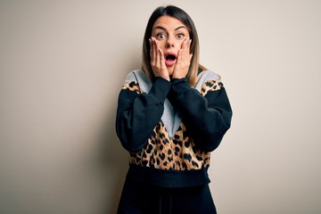 Young beautiful woman wearing casual sweatshirt standing over isolated white background afraid and shocked, surprise and amazed expression with hands on face