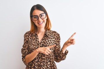Beautiful redhead woman wearing glasses and elegant animal print shirt over isolated background smiling and looking at the camera pointing with two hands and fingers to the side.