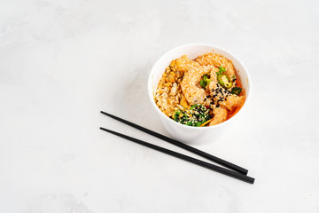 Asian food background with Spicy Shrimp Poke Bowl with rice, seaweeds and sesame seeds, avocado in...