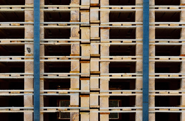Close-up, texture and background of many wooden pallets stacked on top of one another and held together by tension belts