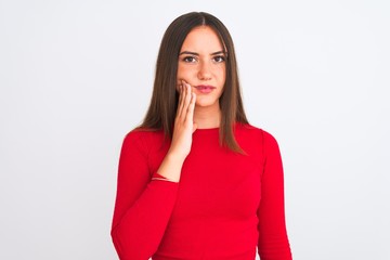 Young beautiful girl wearing red casual t-shirt standing over isolated white background touching mouth with hand with painful expression because of toothache or dental illness on teeth. Dentist