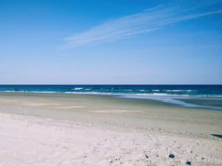 Empty ocean coast. Sea coast without people with white sand, clear sky and blue sea. Small waves and calm in the ocean.