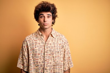 Young handsome man on vacation wearing summer shirt over isolated yellow background depressed and worry for distress, crying angry and afraid. Sad expression.