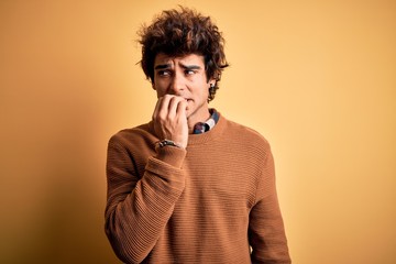 Fototapeta na wymiar Young handsome man wearing casual shirt and sweater over isolated yellow background looking stressed and nervous with hands on mouth biting nails. Anxiety problem.