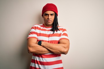 Young handsome african american man with dreadlocks wearing striped t-shirt and wool hat skeptic...