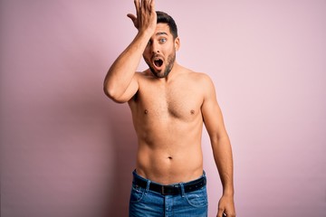 Fototapeta premium Young handsome strong man with beard shirtless standing over isolated pink background surprised with hand on head for mistake, remember error. Forgot, bad memory concept.