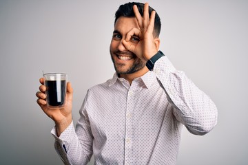 Young handsome man drinking a cup of hot coffee over white isolated background with happy face smiling doing ok sign with hand on eye looking through fingers