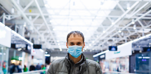 A young man in a medical mask in a shopping center. The masked man protects himself from the epidemic of the Chinese virus "2019-nKoV"