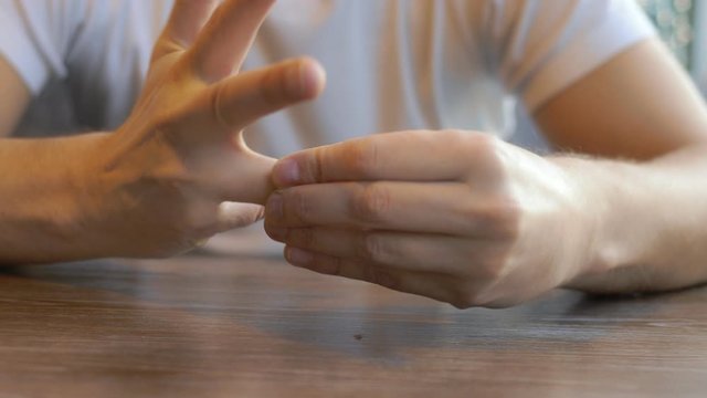 closeup. man takes off a wedding ring while sitting in a cafe.