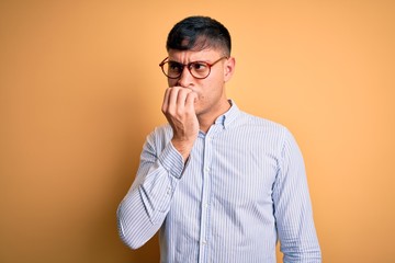 Young handsome hispanic business man wearing nerd glasses over yellow background looking stressed...