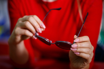 Beautiful young girl chooses sunglasses in an optics store.