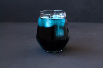 iced butterfly pea tea. glass of blue herbal tea with dry flowers on a black background. Cocktails. Healthy lifestyle. cup of cold tea with dry flowers on a black table. copy space