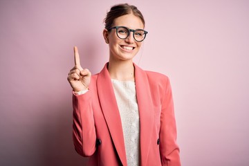 Young beautiful redhead woman wearing jacket and glasses over isolated pink background showing and...