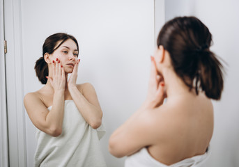 A beautiful girl massages her face with cream; genuine leather models; skin care concept