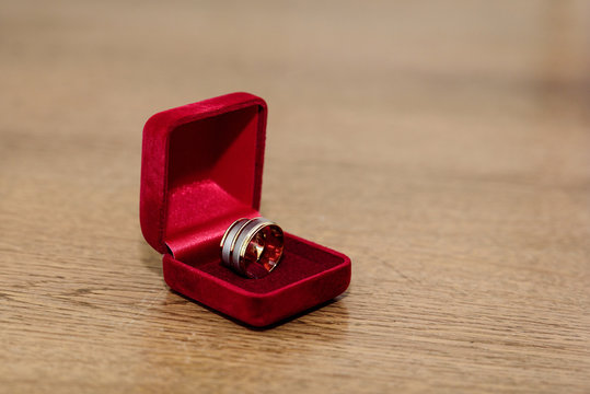 Wedding rings in a box of red velvet on a wooden table. Close up