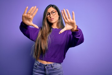 Young beautiful smart woman wearing glasses over purple isolated background doing frame using hands palms and fingers, camera perspective