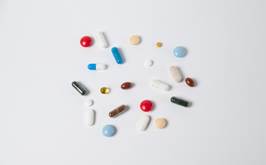 Multicolored medical pills and capsules on a white background, top view
