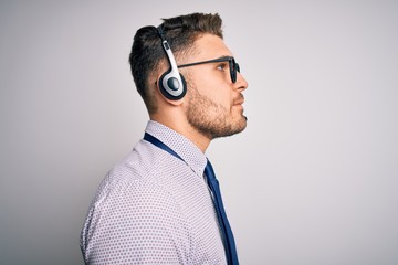 Young call center operator business man with blue eyes wearing glasses and headset looking to side,...