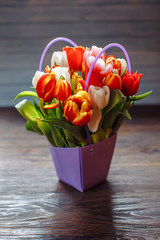 bouquet of different color tulips in purple box on a dark wooden background