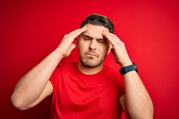 Fototapeta premium Young man with blue eyes wearing casual t-shirt over red isolated background suffering from headache desperate and stressed because pain and migraine. Hands on head.