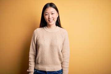 Young beautiful asian woman wearing casual sweater over yellow isolated background with a happy and...