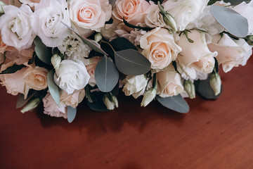 Close up of beautiful modern and stylish wedding bouquet of white, pink roses and eucalyptus greenery on wooden background. Summer floral composition.