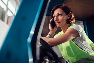 Woman forklift operator talking on the phone in vehicle