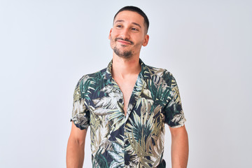 Young handsome man wearing Hawaiian summer shirt over isolated background smiling looking to the...