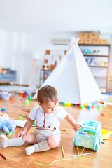 Adorable toddler playing around lots of toys at kindergarten