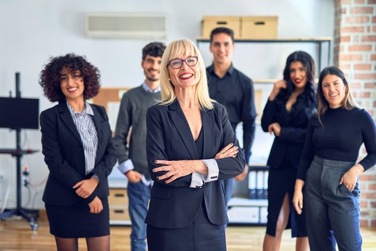 Group of business workers smiling happy and confident. Posing together with smile on face looking at the camera, middle age beautiful woman with crossed arms at the office