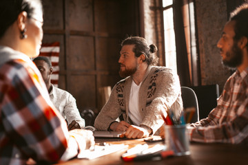 Multi-Ethnic Business Team Of Experienced Employees Working Together Around A Table In A Loft-Style Office. Selective Focus On Caucasian Attractive Guy.