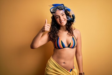 Young beautiful woman with curly hair on vacation wearing bikini and diving googles doing happy...