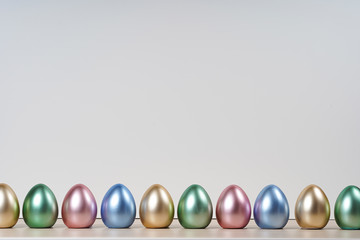 Colorful easter eggs on white wall and wood table.