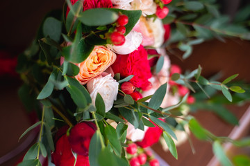 Fototapeta na wymiar Horizontal image of a beautiful, stylish wedding bouquet of red, pink roses and eucalyptus greenery on wooden background. Summer floral composition.