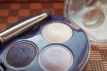 A palette of violet shades of eyeshadow and a brush for eyeshadow. Beauty style. Purple eye shadow for bride makeup. Retro palette of shadows.